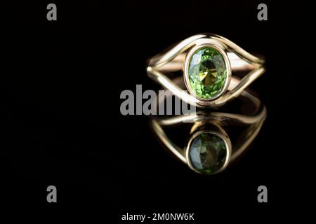 Un anello d'oro da donna su ordinazione lavorato a mano da un artigiano della gioielleria. Nell'anello è montata una grande pietra di cristallo tormalina verde. Foto Stock