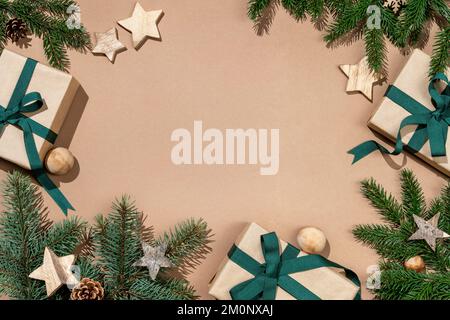 Rami di abete di Natale decorati con stelle di legno e scatole regalo su sfondo beige. Buon Natale e felice anno nuovo concetto Foto Stock