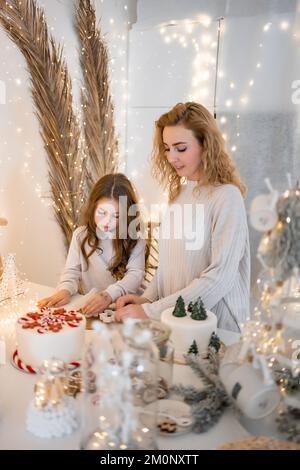 Felice divertente madre e figlia bambino cuocere biscotti di natale in cucina a casa Foto Stock