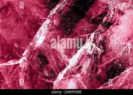 Ghiaccio trasparente blu scuro di lago Baikal congelato con motivo di crepe bianche. Splendido sfondo invernale natura. Immagine colorata in color magenta trendy dell'anno 2023. Foto Stock