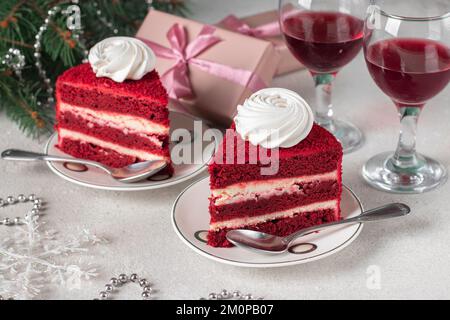 Due porzioni di torta di velluto rosso, vino e regali su sfondo grigio, dessert per il Capodanno Foto Stock