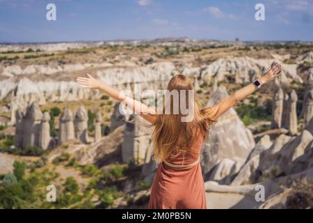 Giovane donna che esplora la valle con formazioni rocciose e grotte delle fate vicino a Goreme in Cappadocia Turchia Foto Stock