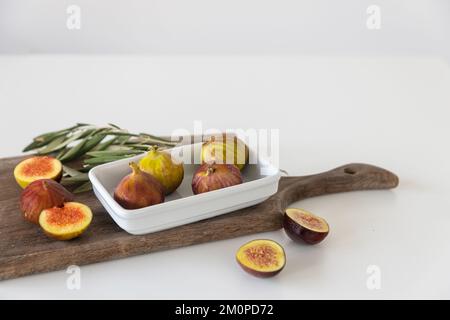 Fiche intere e metà in una lastra di porcellana rettangolare bianca su un tagliere pronto per la colazione. Posiziona per testo Foto Stock