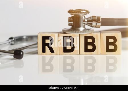 RBBB la parola su cubi di legno, cubi in piedi su una superficie bianca riflettente, su cubi - uno stetoscopio. Concetto di medicina Foto Stock