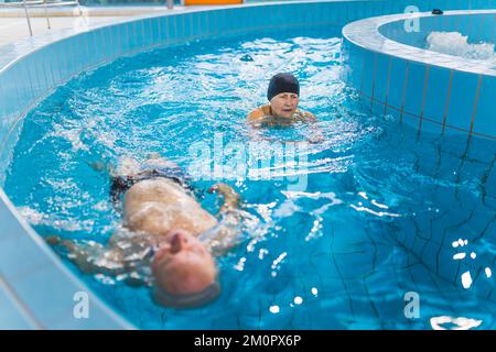 Piscina lazy River. Coppia caucasica sposata che gode il loro tempo libero in modo attivo. Piscina interna. Acqua turchese. Foto di alta qualità Foto Stock