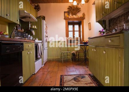 Cucina con armadietti verde oliva all'interno vecchio 1850 Canadiana cottage stile fieldstone casa, Quebec, Canada. Questa immagine è stata rilasciata come proprietà. PR014 Foto Stock