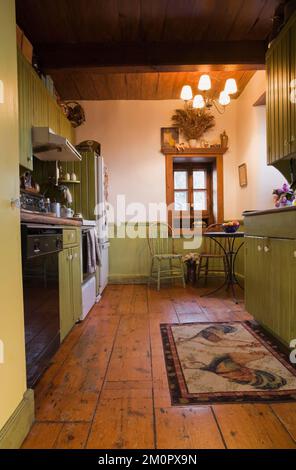 Cucina con armadietti verdi oliva all'interno di una vecchia casa in pietra di campo in stile cottage canadese del 1850. Foto Stock