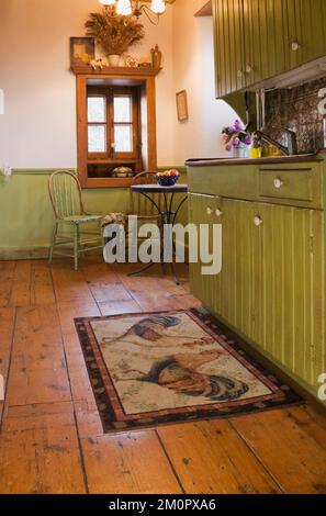 Cucina con armadietti verdi oliva all'interno di una vecchia casa in pietra di campo in stile cottage canadese del 1850. Foto Stock