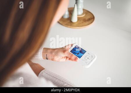 Donna irriconoscibile che guarda la macchina fotografica del bambino che tiene in mano Foto Stock