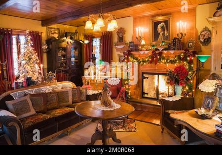 Sontuosamente decorato soggiorno a Natale all'interno 1977 costruito replica di vecchio canadiana cottage in stile chalet in legno 1800s. Foto Stock