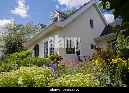 Due piani bianchi degli anni '1950 con finiture nere, casa padronale francese in stile canadese con giardino all'inglese in estate. Foto Stock