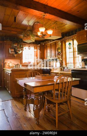 Tavolo da pranzo quadrato e sedie alte arrotondate in cucina rustica all'interno 1977 costruito replica di vecchio canadiana cottage stile 1800s in legno cabina. Foto Stock