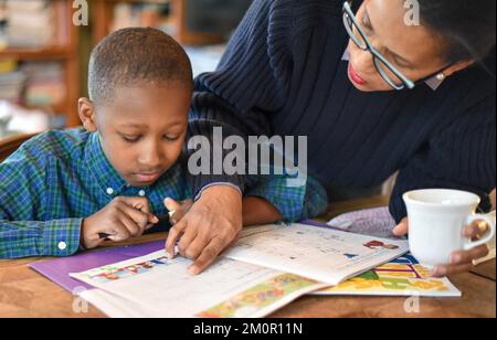 bambino che è tenuto a insegnare a casa, facendo i compiti imparando cose nuove e nuove tecniche di insegnamento Foto Stock