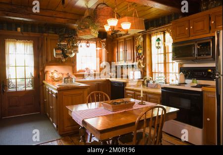 Tavolo da pranzo quadrato e sedie alte arrotondate in cucina rustica all'interno 1977 costruito replica di vecchio canadiana cottage stile 1800s in legno cabina. Foto Stock