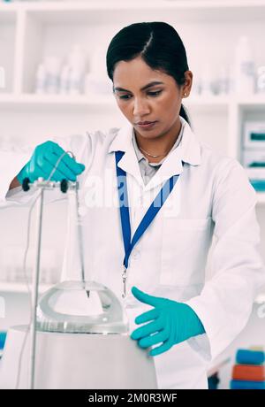 Condurre esperimenti per testare le sue teorie. una giovane e attraente scienziata che lavora con una centrifuga in un laboratorio. Foto Stock