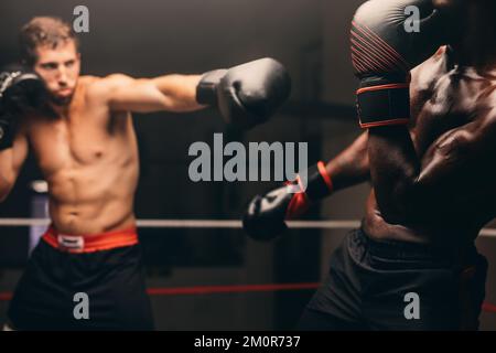 Boxer ha perso il suo avversario durante una lotta in un anello di boxe. Due pugili maschi che hanno una partita di pugilato in palestra. Foto Stock