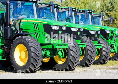 Primo piano dei trattori agricoli John Deere 6155R parcheggiati in un cortile di fila in una giornata di sole all'inizio dell'autunno. Lieto, Finlandia. Settembre 22, 2022. Foto Stock