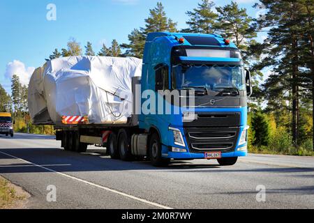 Blue Volvo FH semirimorchio in convoglio di grandi trasporti di carichi verso il porto di Hanko assistito da veicoli pilota e di scorta. Raasepori, Finlandia. 23 settembre 2022 Foto Stock