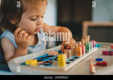 Bambina che gioca con pezzi di legno colorati con numeri. Istruzione scolastica. Stile di vita felice. Concetto di stile di vita della gente. Foto Stock