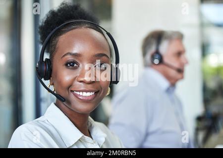 Al vostro servizio. un giovane e attraente agente del call center seduto con la sua collega in ufficio. Foto Stock