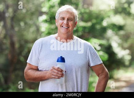 Mantenere l'idratazione è importante per la salute e le prestazioni. Ritratto di un uomo maturo che beve acqua mentre si esercita all'aperto. Foto Stock