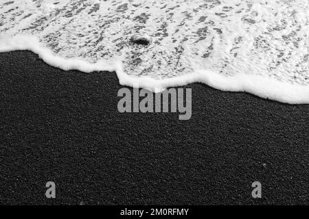Il contrasto tra la laguna color smeraldo e i grani neri della spiaggia è così sorprendente Foto Stock