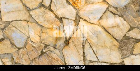 Robusto muro in pietra con taglio giallo e beige, ideale per sfondi, senza cuciture allineate Foto Stock