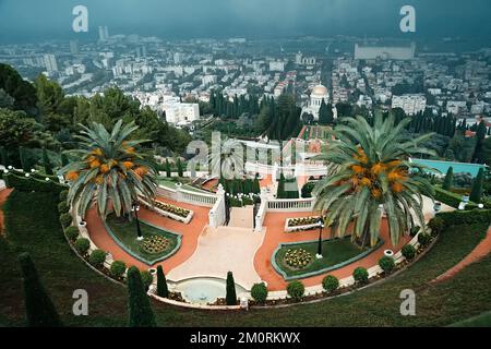 Vista del Santuario del Bab e delle terrazze al Bahai World Center di Haifa, Israele sullo sfondo di una città annebbiato in una giornata nuvolosa. Bellezza del Foto Stock