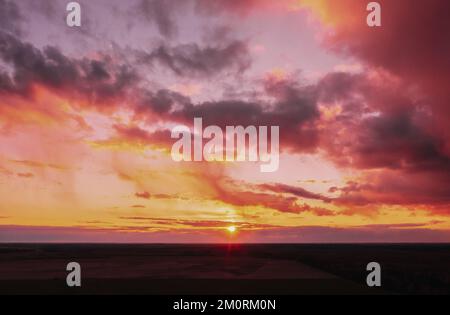 Tramonto alba cielo colorato su campo o prato. Cielo luminoso e drammatico e terreno scuro. Paesaggio di campagna sotto paesaggistico incredibile naturale luminoso Foto Stock