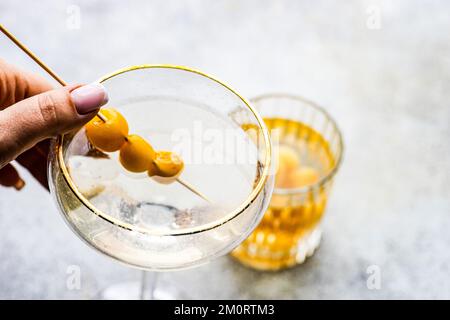 Primo piano di una donna che si avvicina per un cocktail di vodka e un tumbler riempito di ciliegie giallo glace Foto Stock