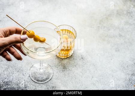 Primo piano di una donna che si avvicina per un cocktail di vodka e un tumbler riempito di ciliegie giallo glace Foto Stock