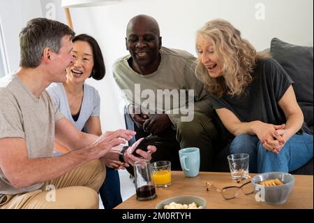 Gruppo di amici di mezza età che si divertono a casa Foto Stock