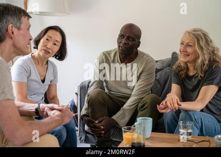 Two senior couples talking while gathered in living room Stock Photo