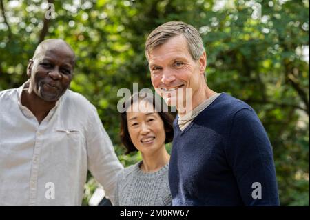 Portrait of middle age diverse group of friends gathered at public park Foto Stock