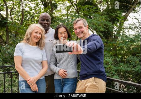 Ritratto di coppie diverse che si divertono mentre scattano un selfie nel parco pubblico Foto Stock