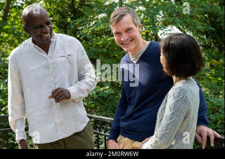 Fun diverse group of middle-aged friends chatting at local park Foto Stock