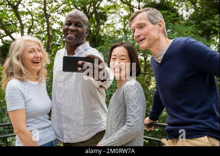 Ritratto di coppie diverse che si divertono mentre scattano un selfie nel parco pubblico Foto Stock
