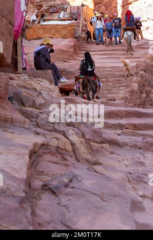 Petra, Giordania - 3 novembre 2022: Asini e persone sulla strada per il monastero, ad Deir Trail nella famosa città antica Foto Stock