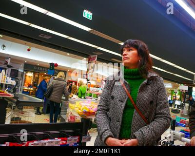 Cremona, Italia - Dicembre 2022 donna ispanica latina al cassiere in supermercato per la spesa Foto Stock