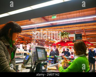 Cremona, Italia - Dicembre 2022 donna ispanica latina al cassiere in supermercato per la spesa Foto Stock