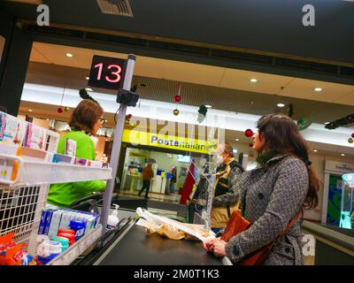 Cremona, Italia - Dicembre 2022 donna ispanica latina al cassiere in supermercato per la spesa Foto Stock