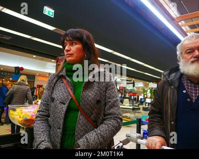 Cremona, Italia - Dicembre 2022 donna ispanica latina al cassiere in supermercato per la spesa Foto Stock