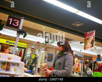 Cremona, Italia - Dicembre 2022 donna ispanica latina al cassiere in supermercato per la spesa Foto Stock