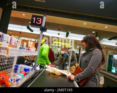Cremona, Italia - Dicembre 2022 donna ispanica latina al cassiere in supermercato per la spesa Foto Stock