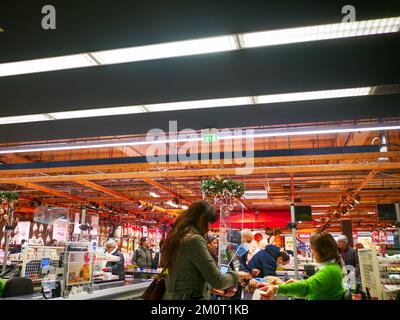 Cremona, Italia - Dicembre 2022 donna ispanica latina al cassiere in supermercato per la spesa Foto Stock