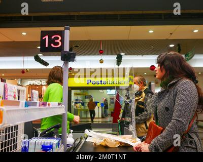 Cremona, Italia - Dicembre 2022 donna ispanica latina al cassiere in supermercato per la spesa Foto Stock