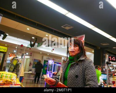 Cremona, Italia - Dicembre 2022 donna ispanica latina al cassiere in supermercato per la spesa Foto Stock