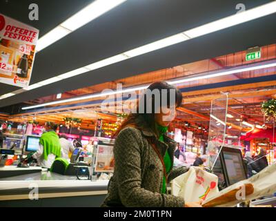 Cremona, Italia - Dicembre 2022 donna ispanica latina al cassiere in supermercato per la spesa Foto Stock