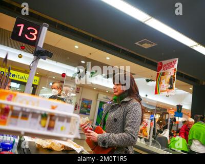 Cremona, Italia - Dicembre 2022 donna ispanica latina al cassiere in supermercato per la spesa Foto Stock