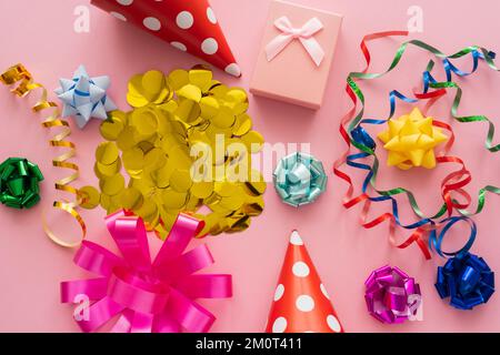 Vista dall'alto di confetti vicino alla serpentina e scatola regalo su sfondo rosa, immagine stock Foto Stock